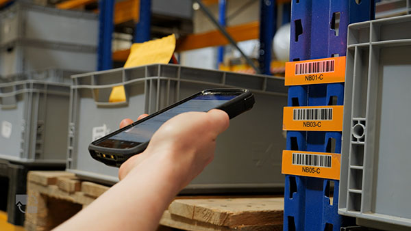 Digital unterstützte Kommissionierung im Lager mit Scanner und Systemanzeige