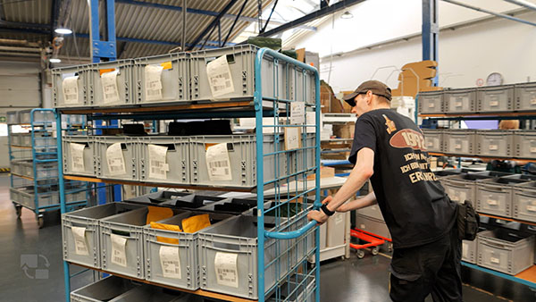 Mitarbeitender kommissioniert Bestellungen in einem Lager mit digital unterstützten Pick-Prozessen 