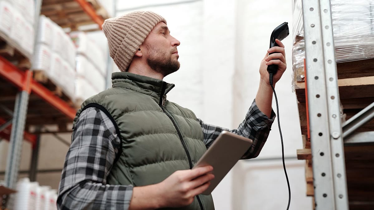 Lagermitarbeiter scannt Artikel im Regal mit einem Handscanner